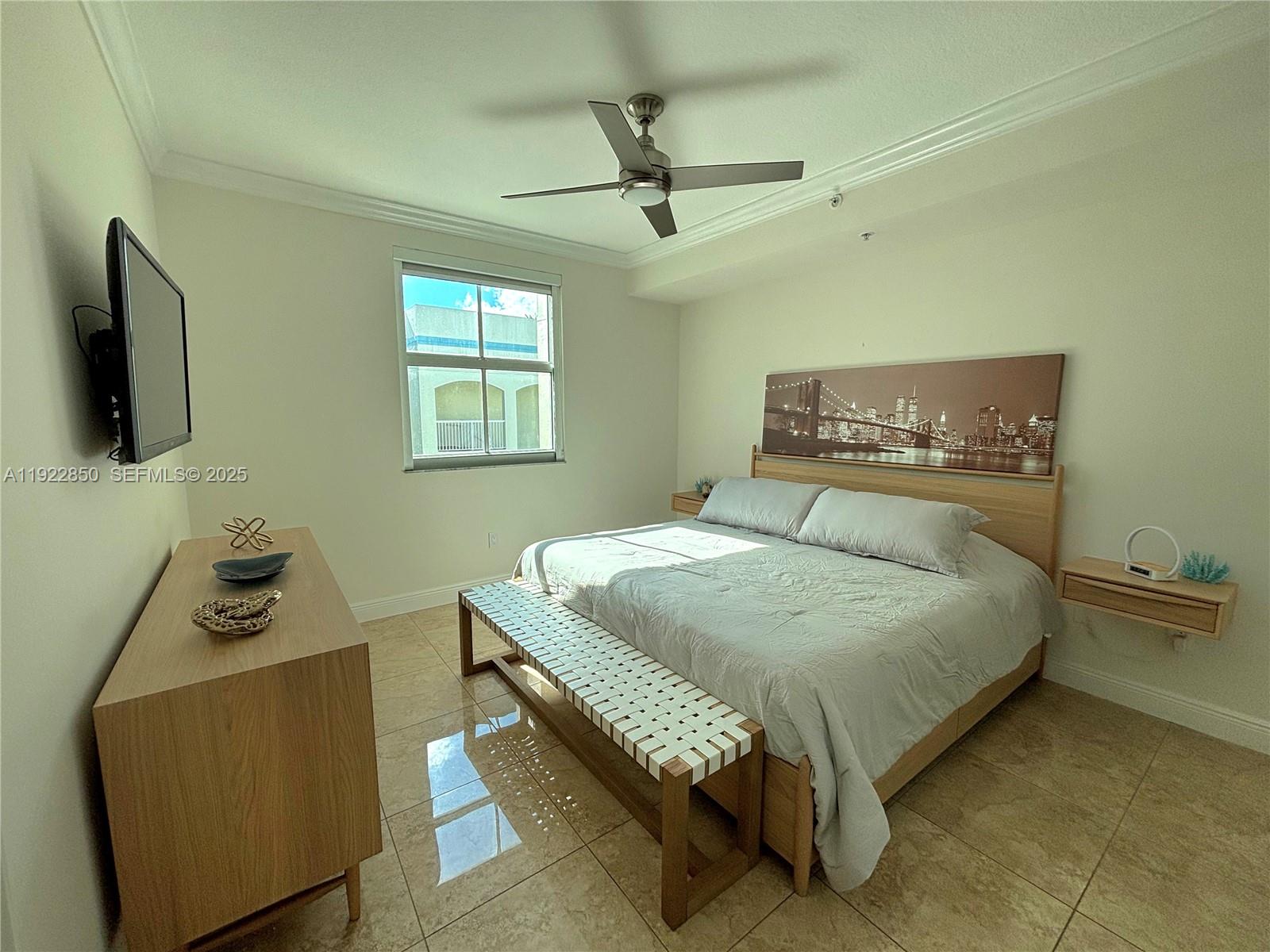 9172 Collins Avenue, Unit 403 Surfside, FL 33154 - Photo 10 of 24 a bedroom with a bed and a flat tv screen on a dresser
