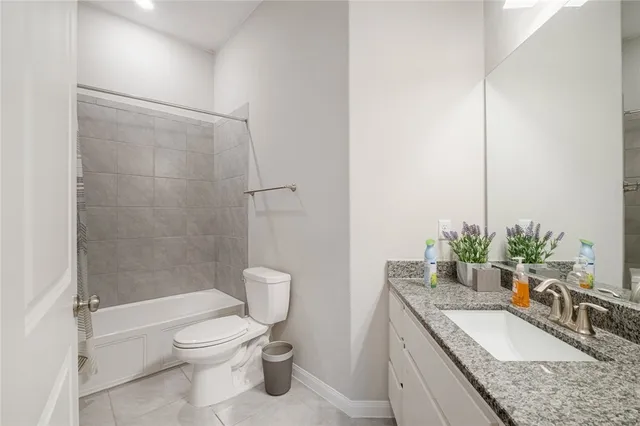 a bathroom with a granite countertop sink a toilet a mirror and shower