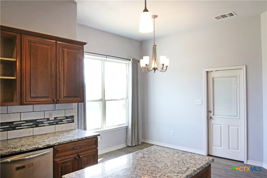 2734 Rock Road Troy, TX 76579 - Photo 12 of 48 a kitchen with granite countertop wooden cabinets a sink a window and stainless steel appliances