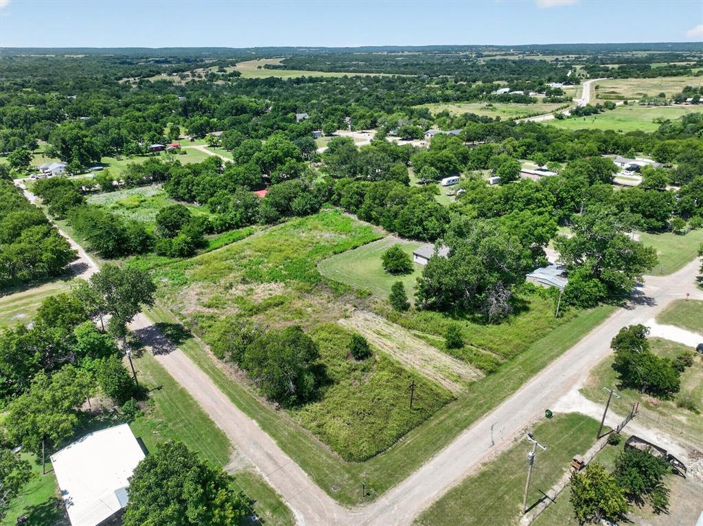 910 Quintard Street Morgan, TX 76671 - Photo 11 of 18 Expansive undeveloped lot with mature trees, surrounded by residential properties and unpaved roads