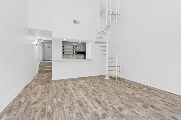 a view of a livingroom with wooden floor and staircase