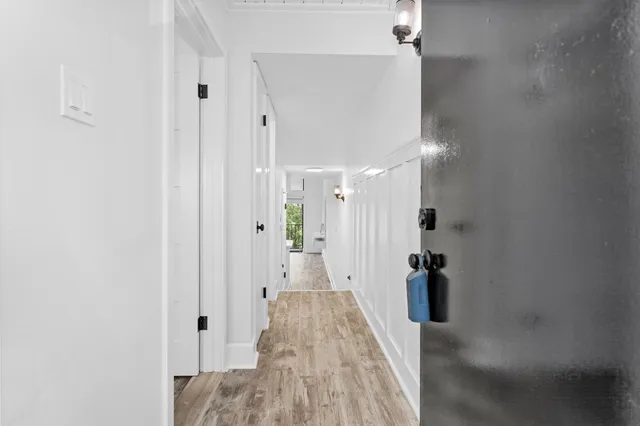 a view of a hallway with wooden floor and a bathroom