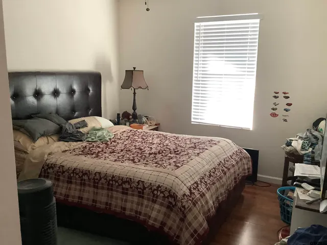 a bedroom with a bed and a lamp with the wooden floor