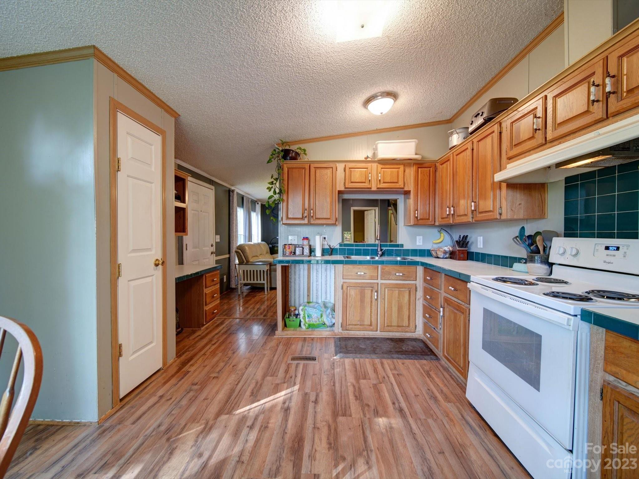1265 Polk Ford Road Stanfield, NC 28163 - Photo 12 of 40 a kitchen with stainless steel appliances granite countertop a stove top oven a sink dishwasher and a refrigerator with wooden floor