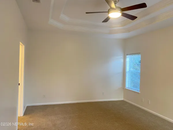 an empty room with windows and fan