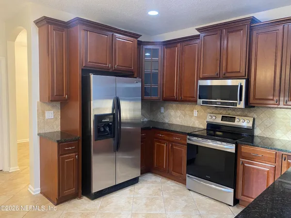 a kitchen with granite countertop wooden cabinets stainless steel appliances and a window