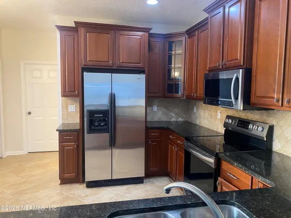 a kitchen with stainless steel appliances granite countertop a refrigerator and a stove top oven