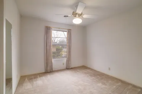an empty room with windows and chandelier fan