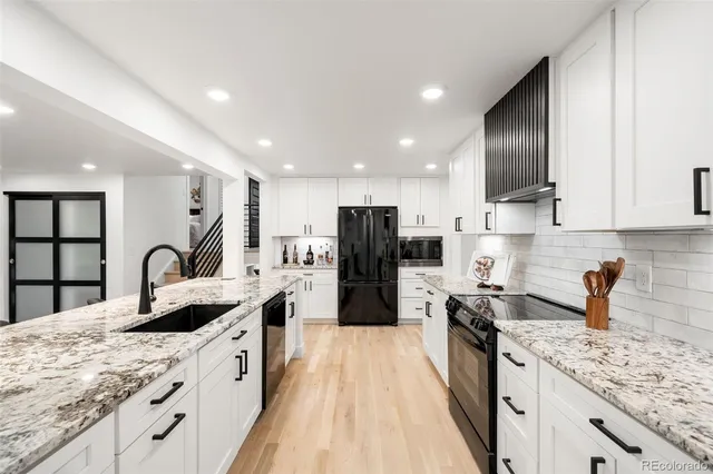 a large kitchen with stainless steel appliances granite countertop a lot of counter space and wooden floors