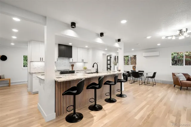 a kitchen with stainless steel appliances kitchen island granite countertop a table chairs sink and cabinets