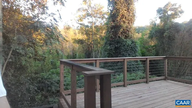 a balcony with wooden floor and fence next to a yard