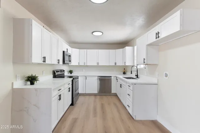 a kitchen with white cabinets appliances and sink