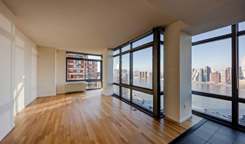 4-75 48th Avenue, Unit 1502 Queens, NY 11109 - Photo 3 of 12 wooden floor in an empty room with a window