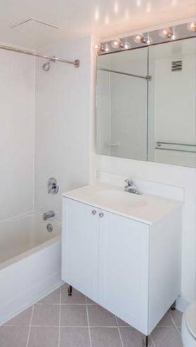 4-75 48th Avenue, Unit 1502 Queens, NY 11109 - Photo 5 of 12 a bathroom with a bathtub sink vanity and mirror