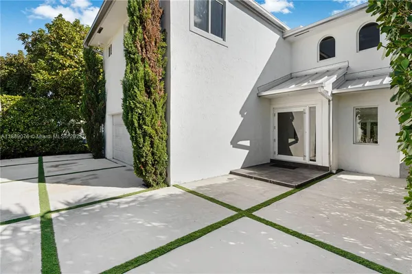 a view of a white house with many windows next to a yard