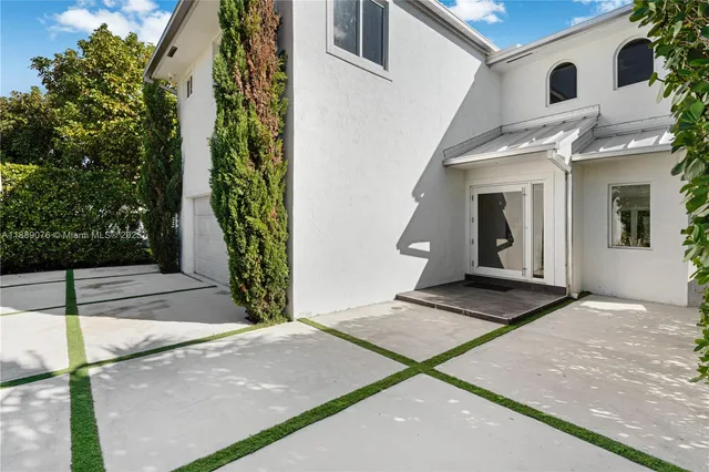 a view of a white house with many windows next to a yard