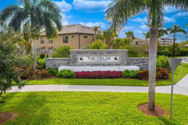 a view of a house with a big yard and palm trees