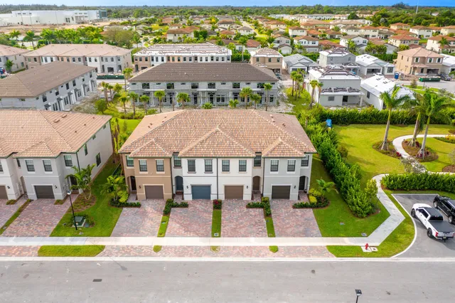 view of an house with swimming pool lawn chairs and large trees