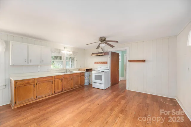 a large kitchen with stainless steel appliances a large counter top a stove a sink and a refrigerator