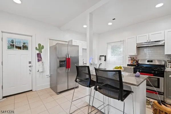 a view of a kitchen with refrigerator and chairs