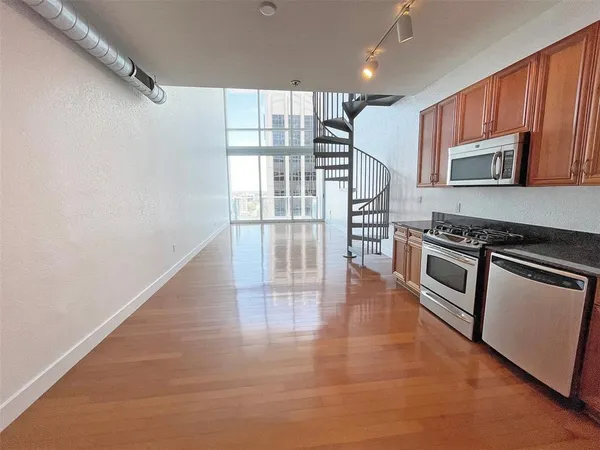 a view of a kitchen with a sink and dishwasher a stove top oven with wooden floor