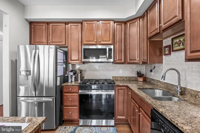 a kitchen with granite countertop a refrigerator stove and sink