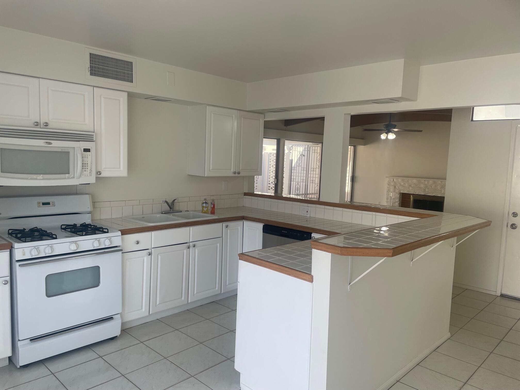 2630 North Biskra Road Palm Springs, CA 92262 - Photo 5 of 10 a kitchen with granite countertop white cabinets and white appliances