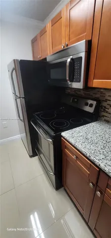 a kitchen with granite countertop a stove microwave and sink