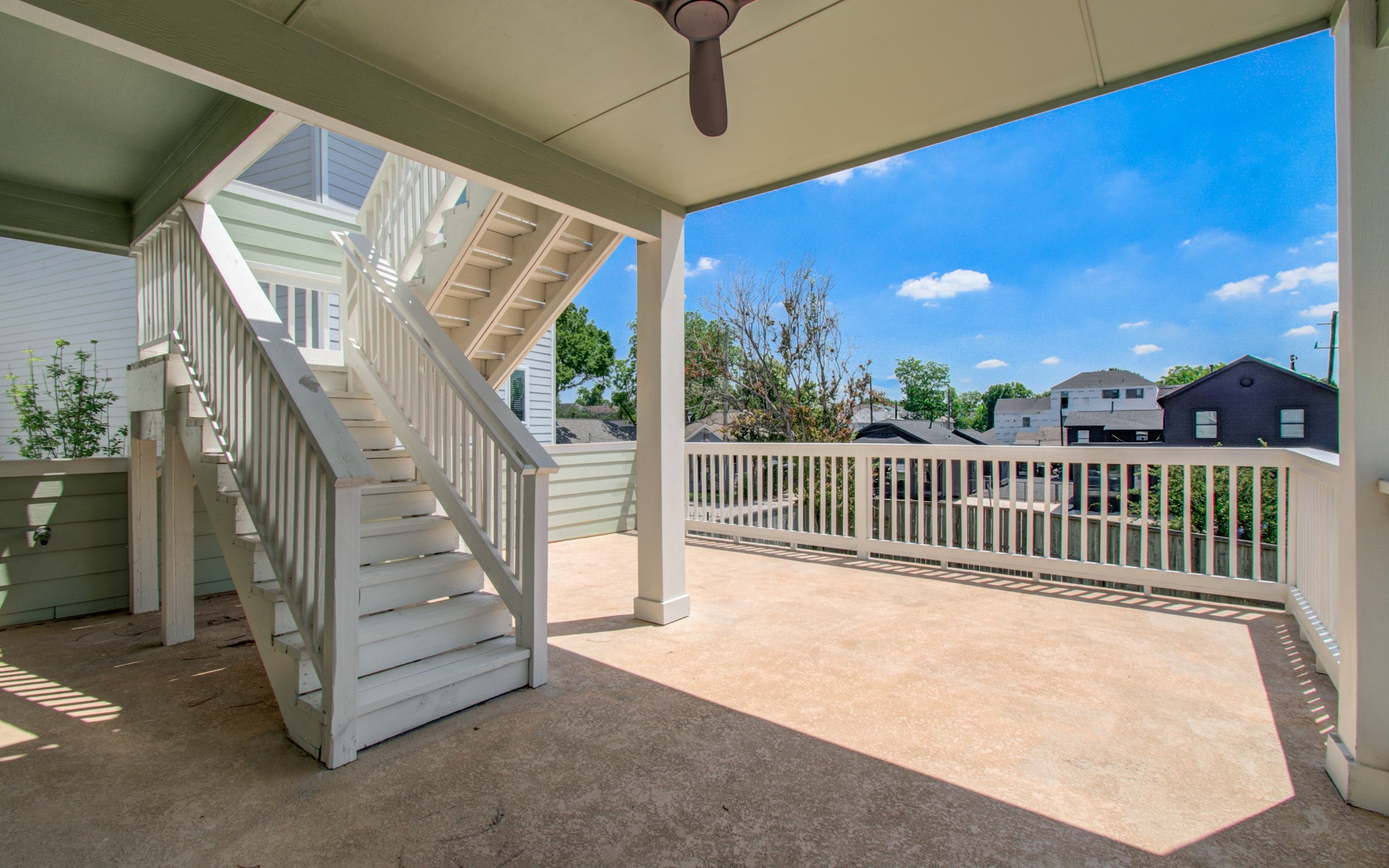 6621 North Main Street Houston, TX 77009 - Photo 20 of 41 This photo showcases a spacious outdoor patio with a ceiling fan, a staircase leading to an upper level, and views of neighboring homes. The area is well-lit and perfect for relaxation or entertaining. Plumbed for full outdoor kitchen ther area is perfect for family entertainment.
