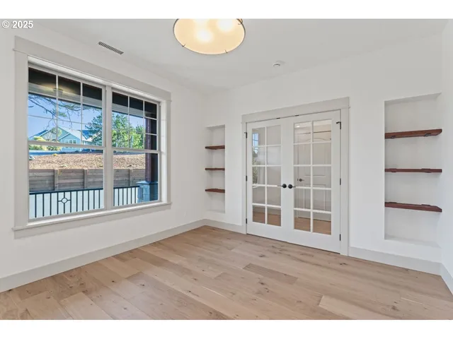 a view of an empty room with a window and wooden floor
