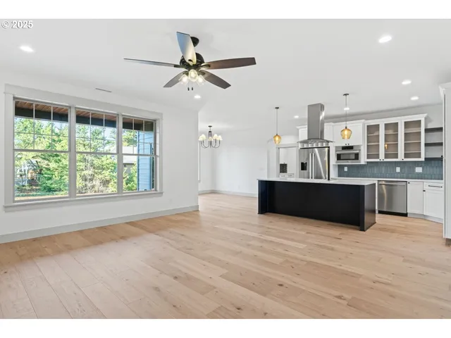 a view of a kitchen with kitchen island a counter top space appliances and a ceiling fan
