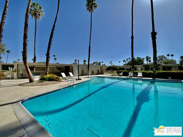 a view of a chairs and table in patio with swimming pool