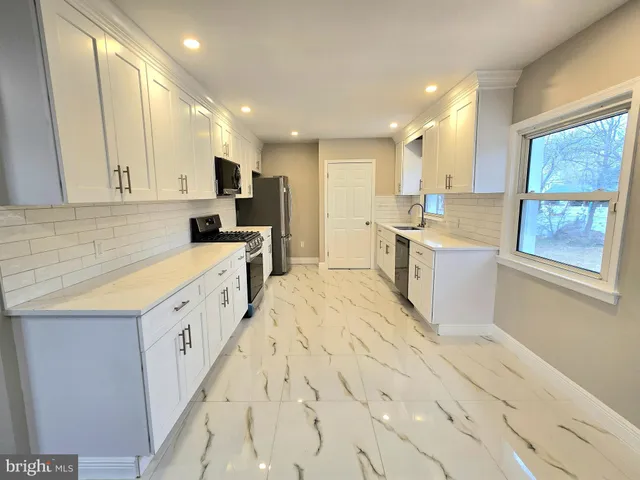 a large kitchen with stainless steel appliances kitchen island granite countertop a sink and cabinets