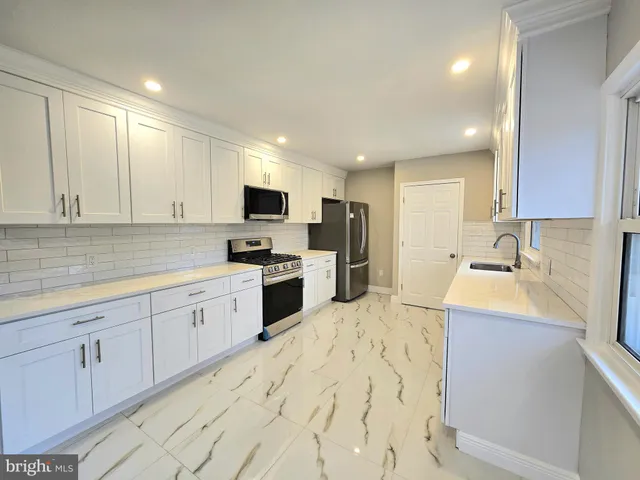 a kitchen with granite countertop a sink stainless steel appliances and white cabinets