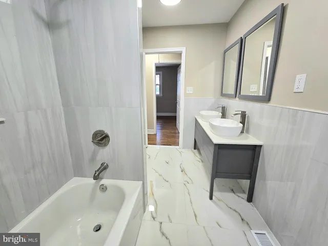 a bathroom with a tub sink and mirror
