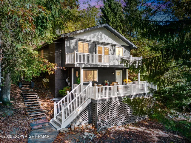 a front view of house along with deck and trees