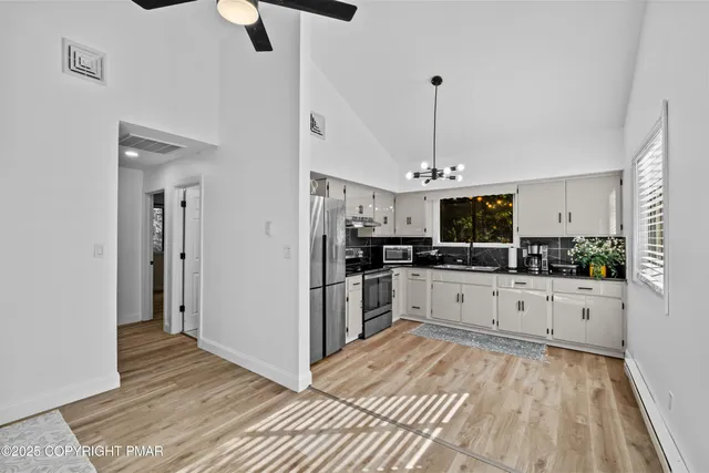 a large kitchen with cabinets wooden floor and stainless steel appliances