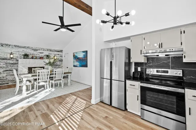 a kitchen with stainless steel appliances a stove a refrigerator cabinets and chairs