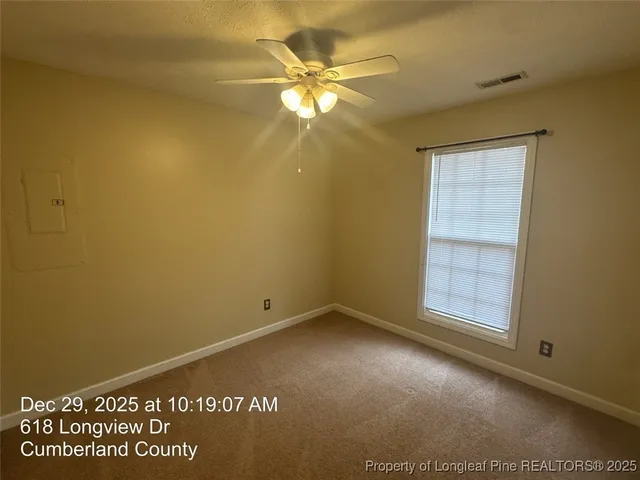 an empty room with windows and fan