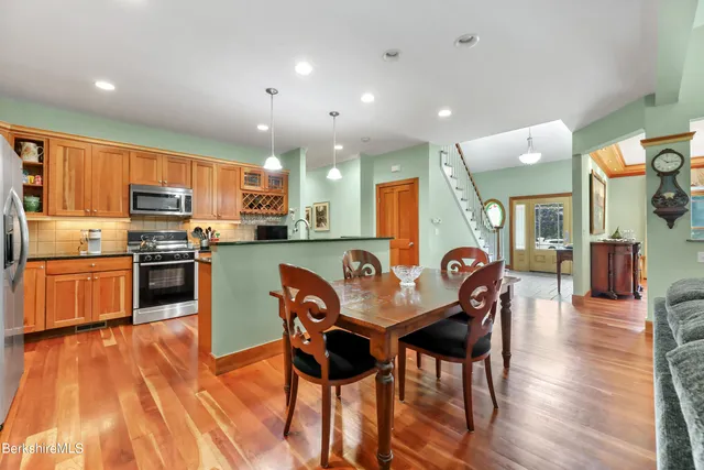 a kitchen with stainless steel appliances kitchen island granite countertop a table chairs and a refrigerator