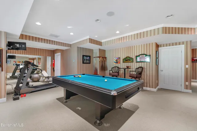 a view of a white house with large windows and a yard with plants and trees