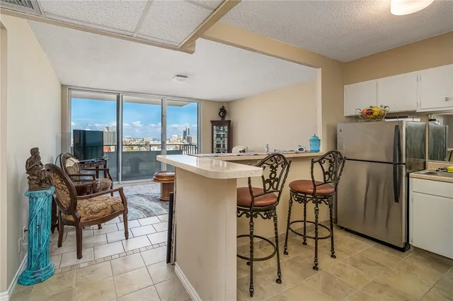 a dining room with stainless steel appliances kitchen island granite countertop a table chairs and a refrigerator