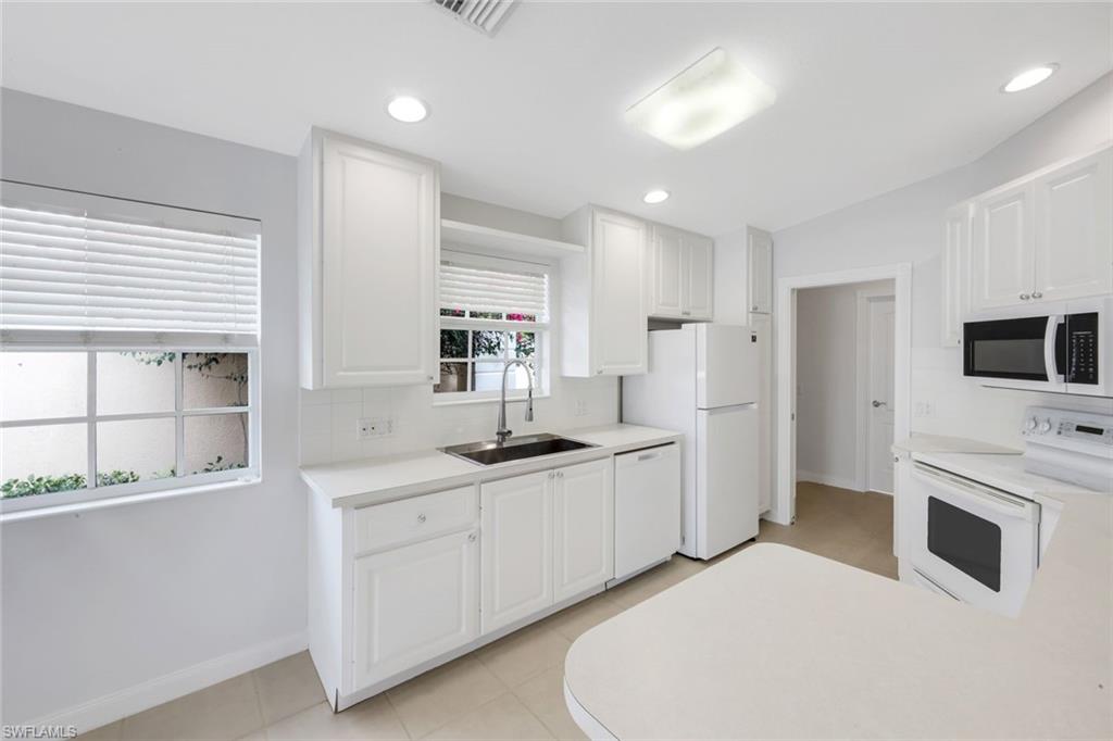 3748 Exuma Way Naples, FL 34119 - Photo 29 of 50 Kitchen with white appliances, light countertops, white cabinetry, light tile patterned flooring, and decorative backsplash