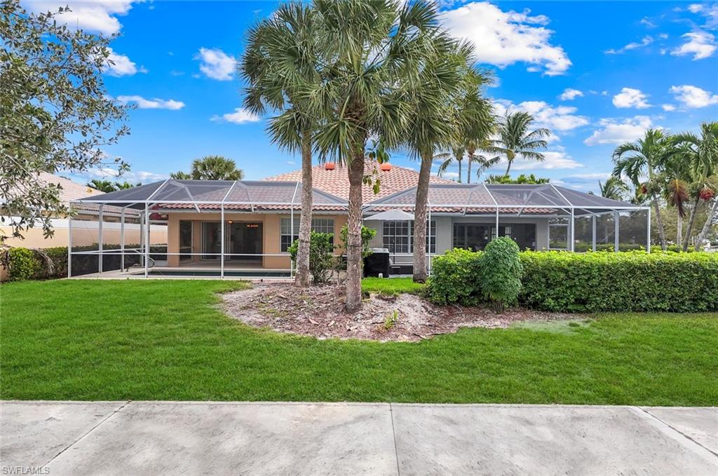 3748 Exuma Way Naples, FL 34119 - Photo 8 of 50 Rear view of house with screen enclosure, lanai, a tiled roof, lawn, and stucco siding