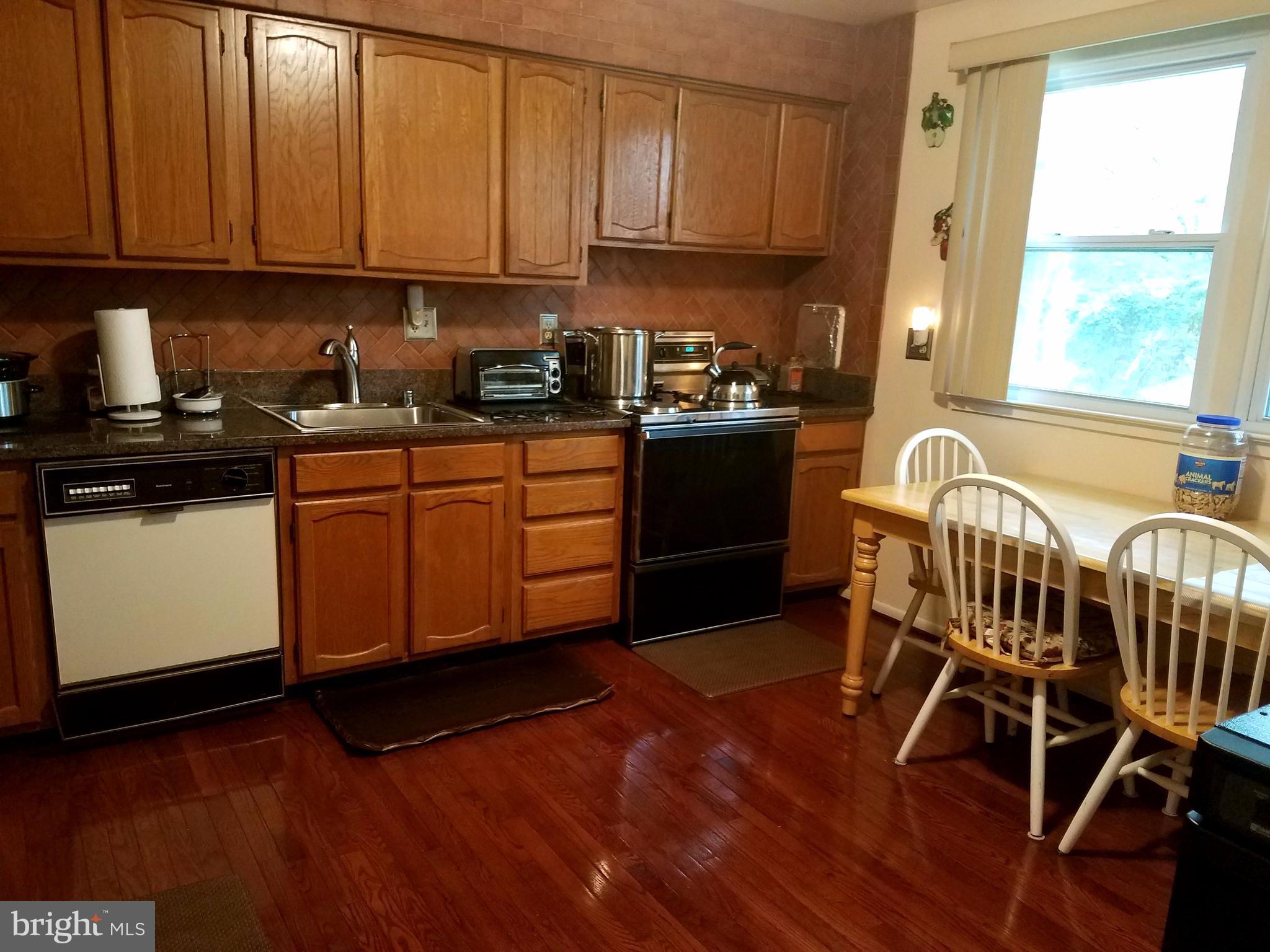 6901 Friendship Road Clinton, MD 20735 - Photo 8 of 26 a kitchen with granite countertop a stove a sink dishwasher and cabinets with wooden floor
