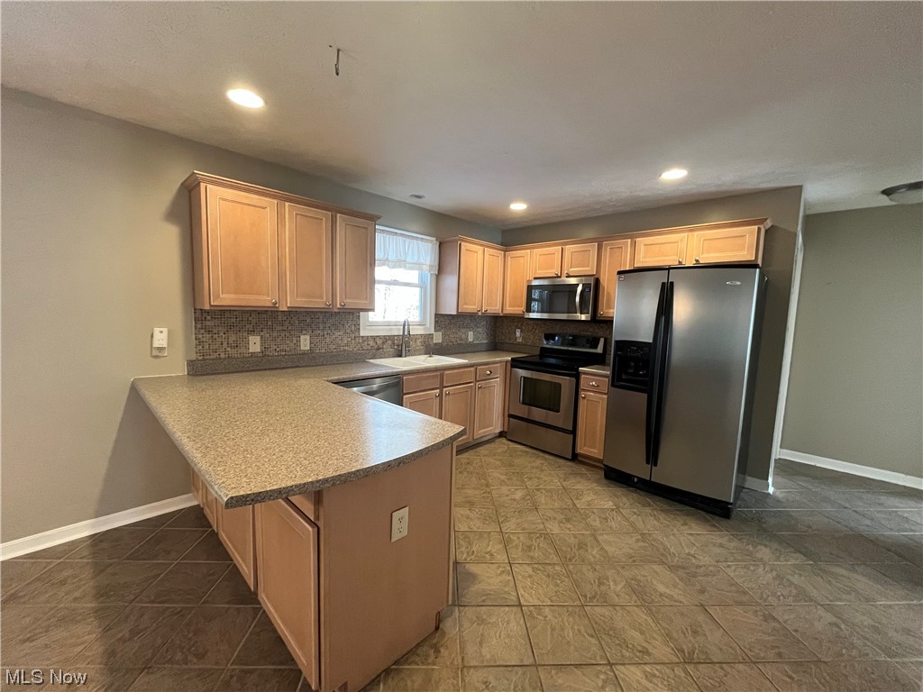 2819 Best Road Cambridge, OH 43725 - Photo 3 of 33 Kitchen featuring stainless steel appliances, dark tile floors, backsplash, kitchen peninsula, and sink