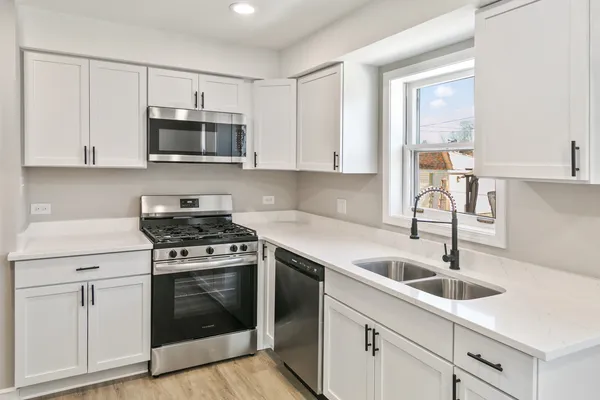 a kitchen with white cabinets stainless steel appliances and sink