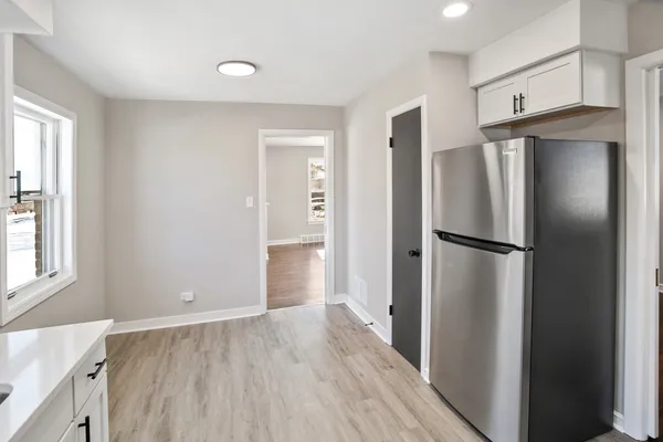 a view of a kitchen with a refrigerator and wooden floor