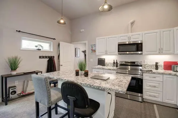a kitchen with granite countertop a sink stainless steel appliances and white cabinets