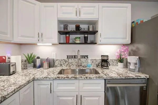 a kitchen with granite countertop a sink a stove and cabinets